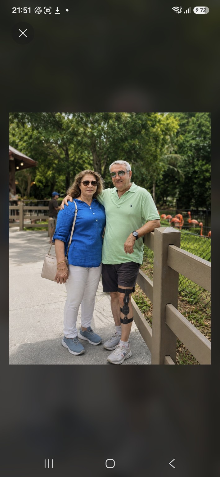 A couple standing together outdoors, with the man wearing a knee support